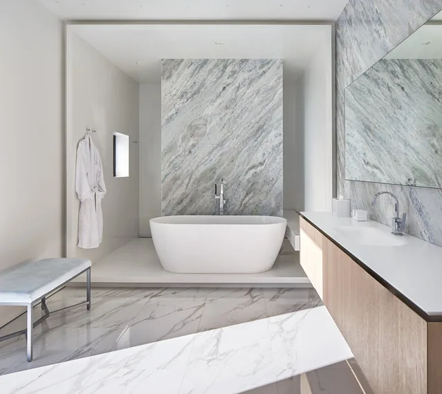 Bathroom features a freestanding tub, marble flooring and wall, and a long vanity with a large mirror.
