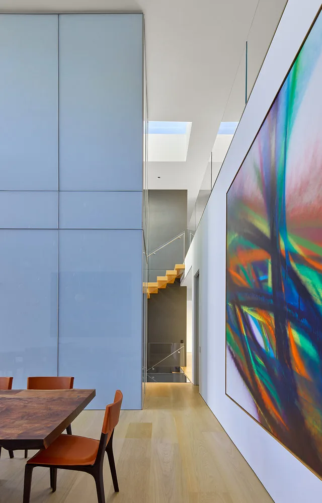 Dining area with light wood flooring, orange leather chairs, and large colorful geometric wall art at Urban Woodland House.