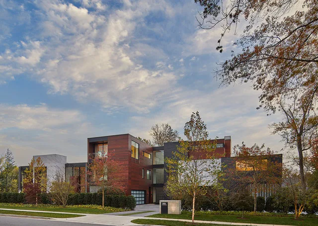 Exterior front view of the Urban Woodland House showcasing wood and dark panel cladding with double-height windows.
