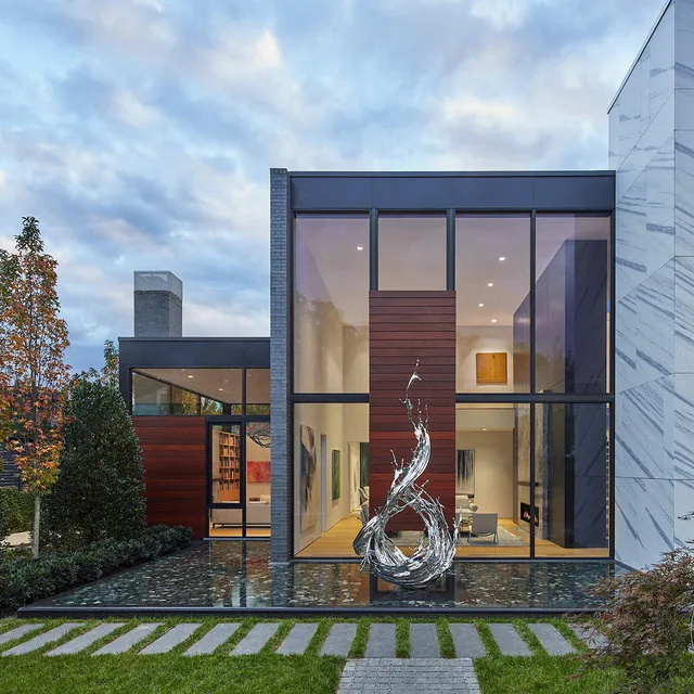 Exterior of Urban Woodland House with floor-to-ceiling glazing and reflecting pool showing a sculptural water feature.