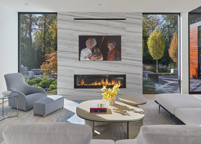 Living room features a floor-to-ceiling marble fireplace with a linear fire and large glass windows providing views of the garden.