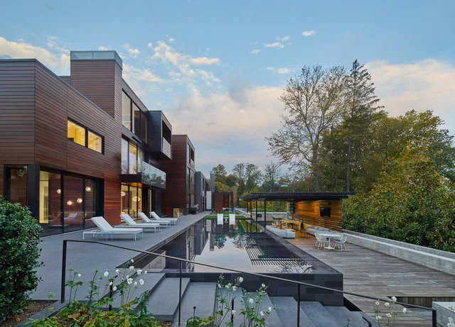 Exterior view of the Urban Woodland House featuring a reflecting pool and outdoor lounge area at dusk.