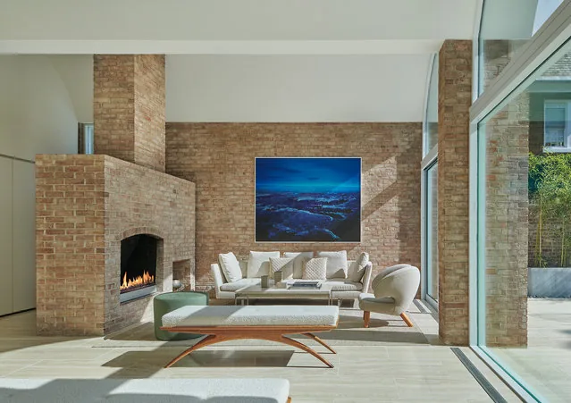 Living area showcasing a brick fireplace and floor-to-ceiling glass windows beside modern seating arrangement.