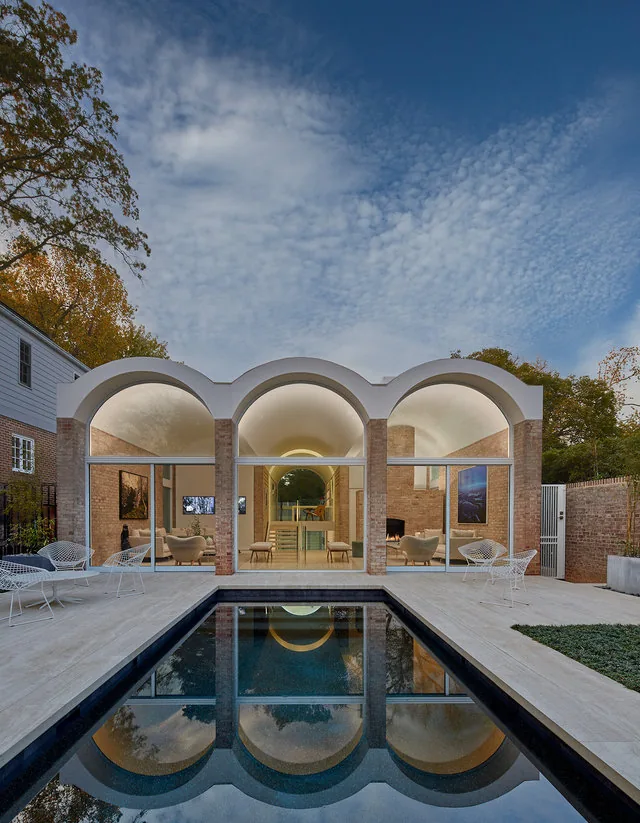 SLAYTON HOUSE RENOVATION AND ADDITION features a modern outdoor living space with barrel vault architecture and a reflecting pool.