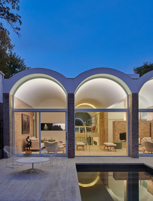 The Slayton House features arched vaulted ceilings and large glass walls facing a pool patio area.