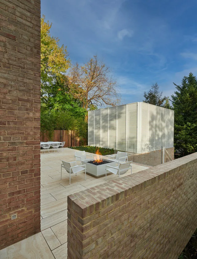 The Slayton House features a brick privacy wall and a modern outdoor seating area with a fire pit.