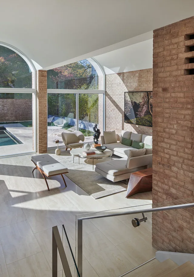 Living room with brick walls, large arched windows, modern seating, and abundant natural light.