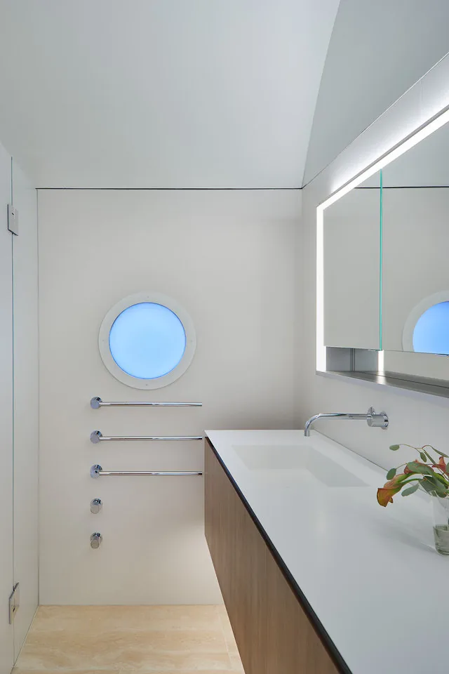 Bathroom with a floating vanity, wall-mounted faucet, and an illuminated mirror above the sink.
