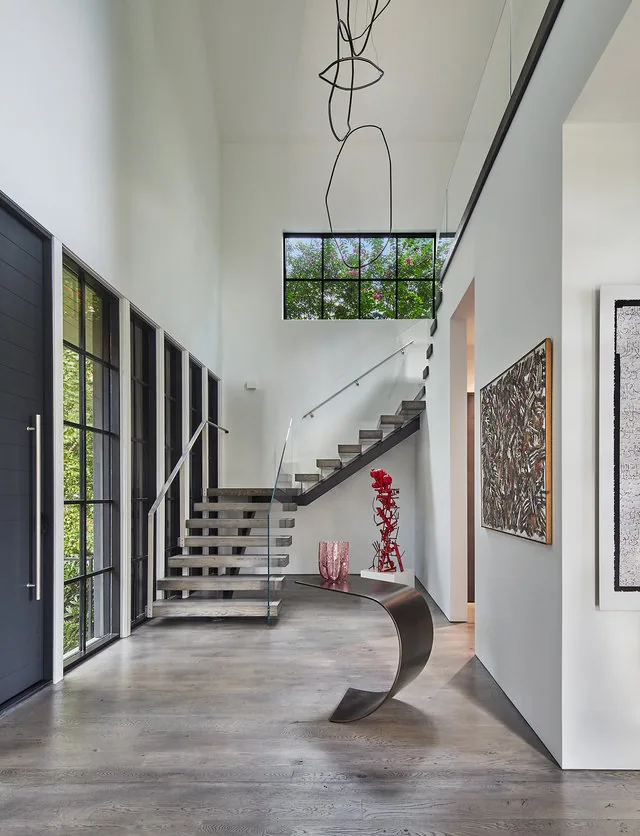 PHILLIPS PARK HOUSE entry hall with floating stairs and black grid windows by Robert Gurney Architects.