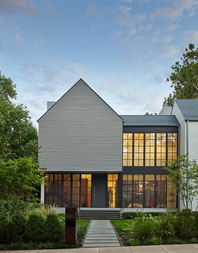 PHILLIPS PARK HOUSE features large grid windows and a modern exterior with a mix of siding and white brick chimney visible.