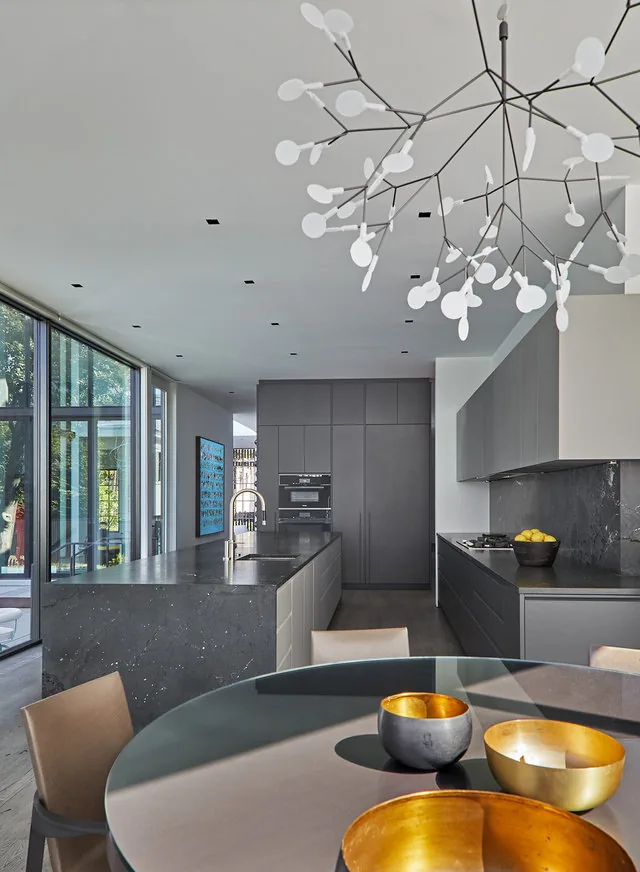 Modern kitchen with grey cabinetry, large island, and a distinctive light fixture over the dining area.