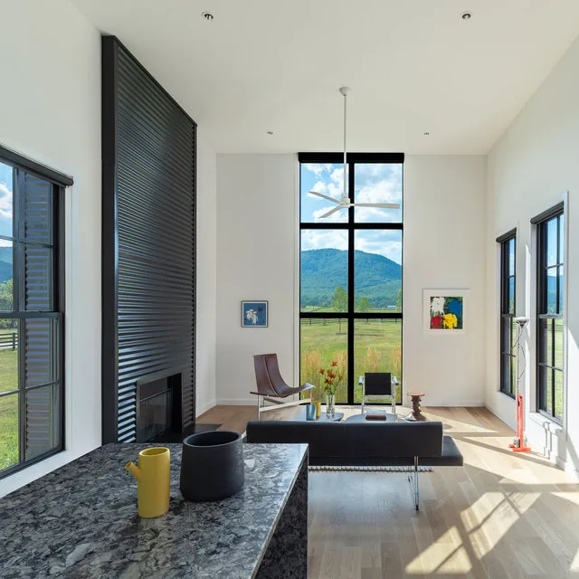 Living area features floor-to-ceiling glazing with black window frames and a black modern fireplace wall.