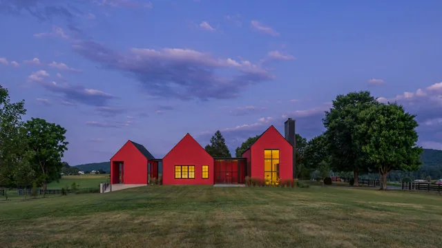 ETLAN FARM HOUSE features a red exterior and black window frames, situated in a rural pasture with mountain views.