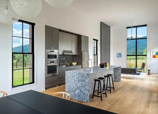 Kitchen in ETLAN FARM HOUSE with granite countertop island and expansive windows framing mountain views.