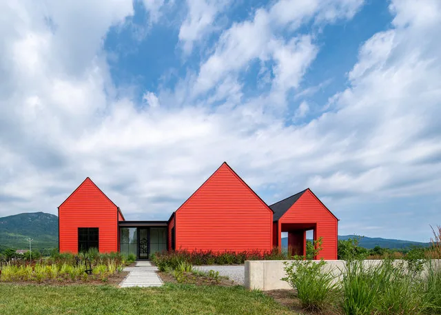 ETLAN FARM HOUSE features bright red exterior siding with three distinct gable roof volumes and black window frames.