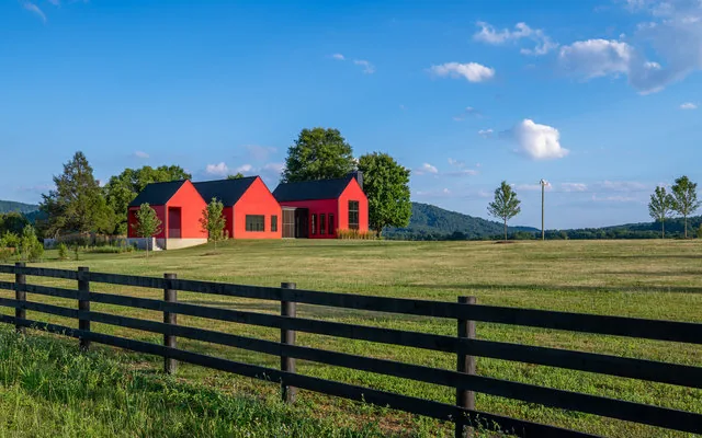ETLAN FARM HOUSE features three red gabled volumes set in a rural landscape with a mountain backdrop.