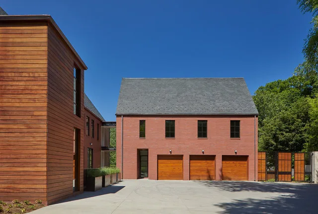 The 30TH STREET HOUSE features a symmetrical red brick facade with a steep gable roof and three wooden garage doors.