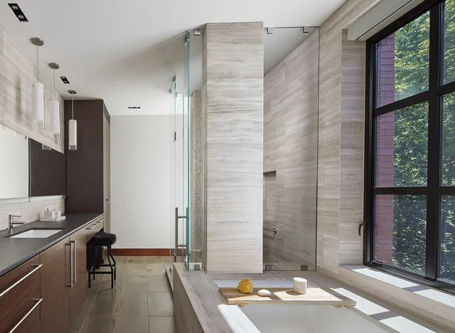 Bathroom featuring a bathtub by a large grid window and a long dark wood vanity with pendant lights.