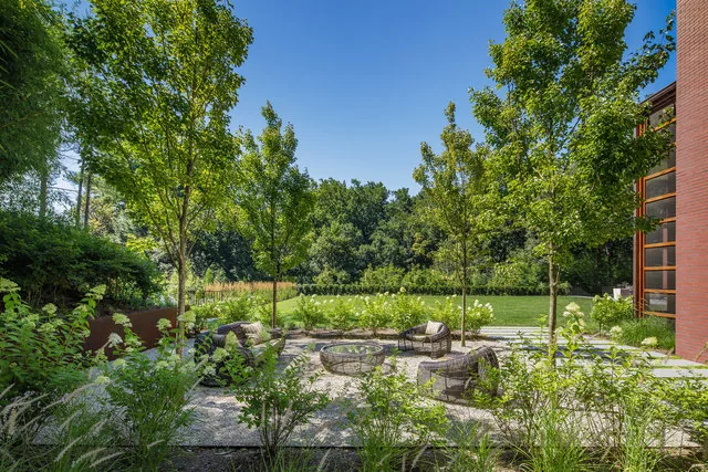 Gravel patio with wicker outdoor furniture and young trees at the 30TH STREET HOUSE by Robert Gurney Architects.