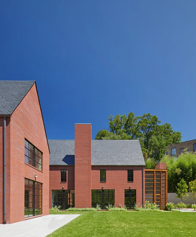 30TH STREET HOUSE features red brick with symmetrical facade, steep gable roofs, and a tall chimney in a landscaped garden setting.