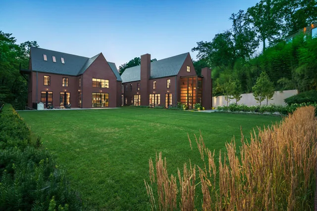 Rear exterior of 30TH STREET HOUSE showing steep-pitched roofs, expansive brick walls, and large vertical windows framed by landscaping.