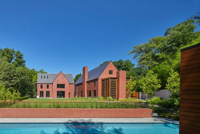 The 30TH STREET HOUSE features steep roof pitches and brick exterior walls, with vertical window panels and a rectangular fireplace.