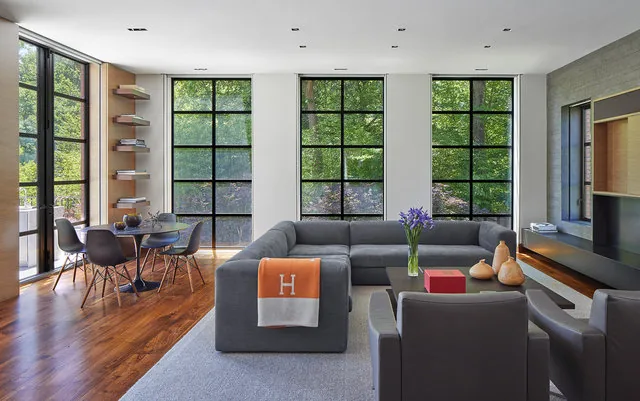 The 30TH STREET HOUSE features a living room with large black window frames and a small dining nook with wood flooring.