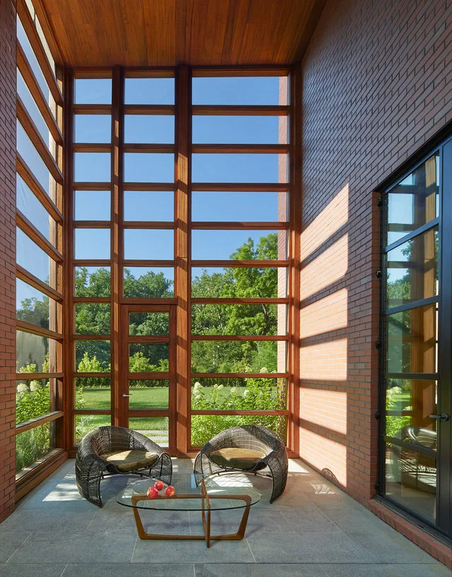The 30TH STREET HOUSE features a glazed porch with large wood-framed windows and brick walls.