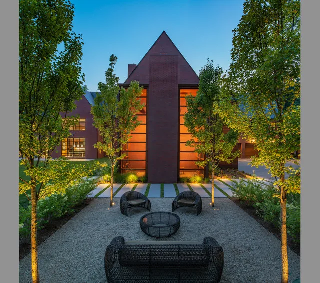 Exterior courtyard view at twilight with woven chairs and lighting highlighting trees and brick facade of 30TH STREET HOUSE.