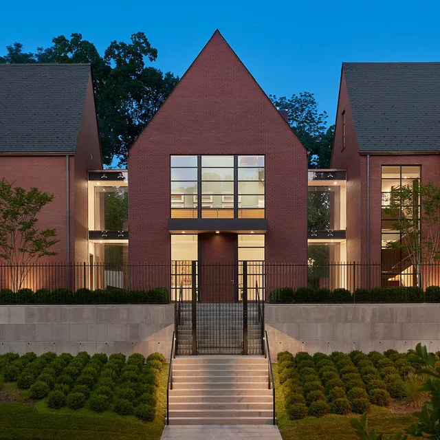 The 30TH STREET HOUSE features steep pitched roofs and vertical window panels in a symmetrical brick facade by Robert Gurney Architects.
