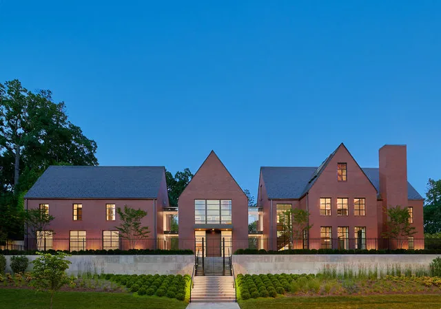 The 30TH STREET HOUSE features three steep-pitched brick buildings connected with glass links under clear evening sky.