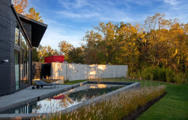 PTR HOUSE features a modern exterior with black vertical siding, an angular roof, and a reflecting rectangular pool surrounded by autumn landscaping.