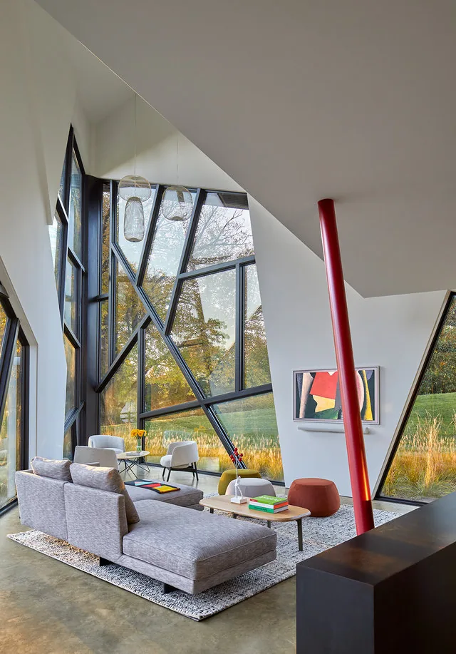PTR HOUSE living room with angular black-framed windows and a red support column by Robert Gurney Architects.