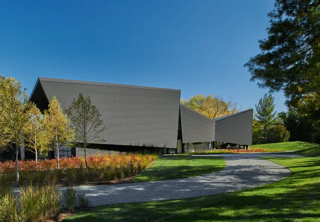 PTR HOUSE by Robert Gurney Architects features angular design, dark wood siding, and a sloped metal roof edge.