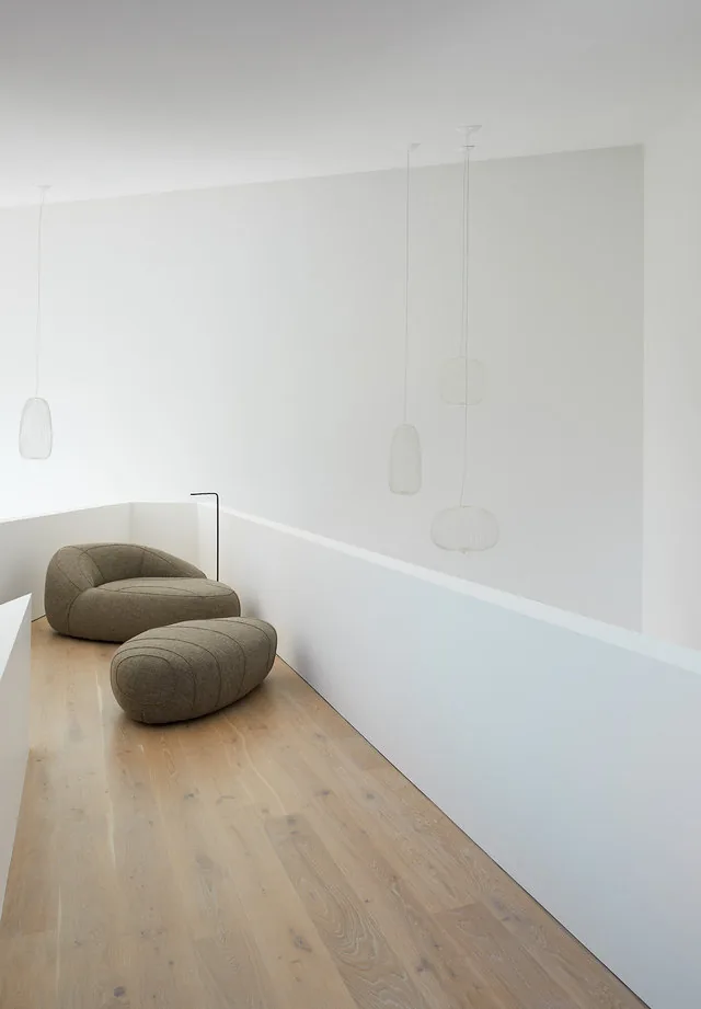 The PTR HOUSE features a minimalist landing with light wood floors and contemporary seating by Robert Gurney Architects.