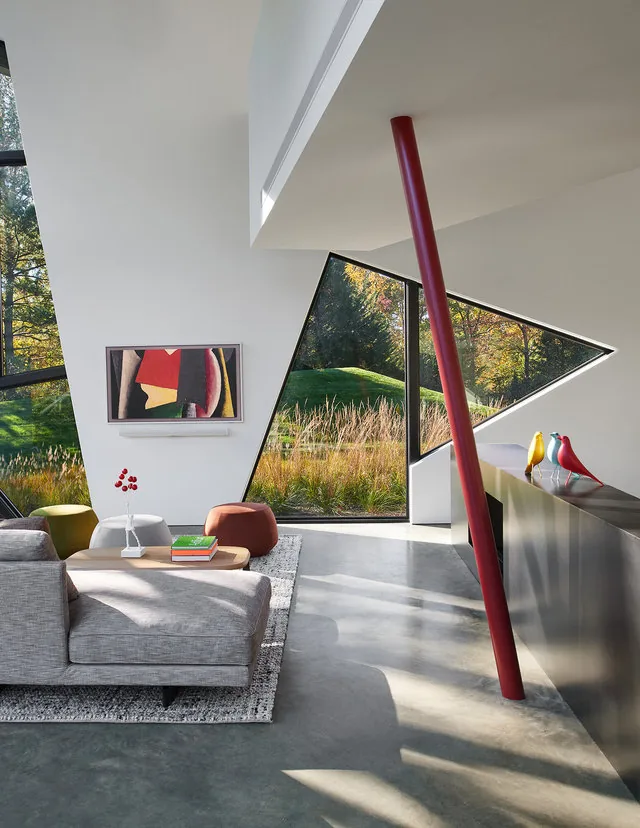 PTR HOUSE living room features triangular windows and an angular wall design with a prominent red slanted column.