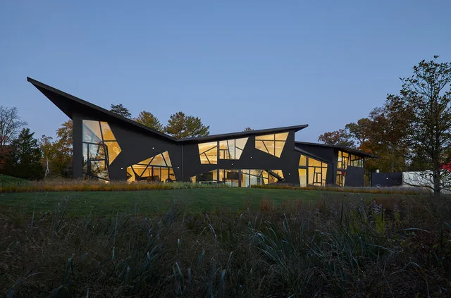 PTR HOUSE features angular roofs and triangular windows with a landscaped lawn in front.
