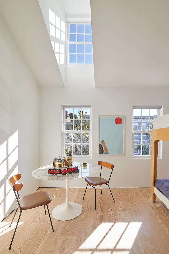 RENOVATION 1662 by Robert Gurney Architects shows a double-height room with light wood flooring and multiple windows.