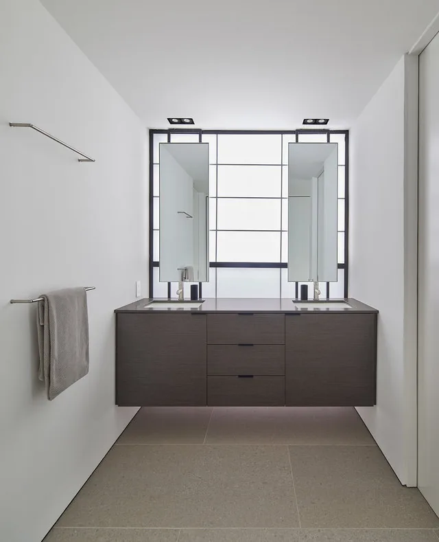 Modern bathroom featuring a floating double vanity with two mirrors and black window frames with frosted glass.