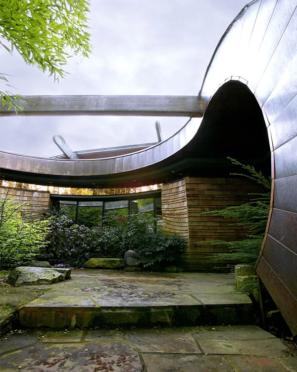 The Wilkinson Residence features a curved courtyard with stone floors, wood siding, and an open circular roof design by Robert Harvey Oshatz Architect.
