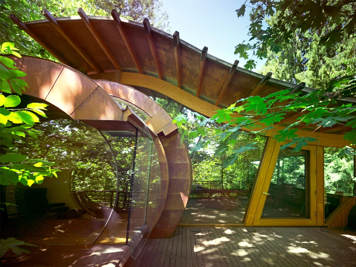The Wilkinson Residence features a circular window and an arched wooden roof in a forested setting.