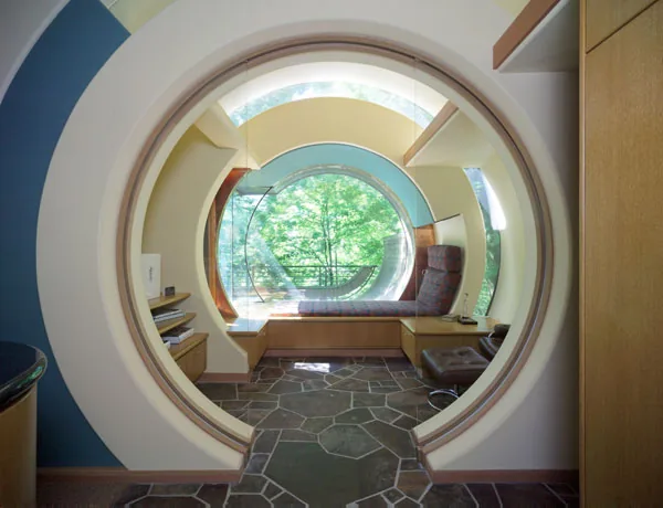 Inside the Wilkinson Residence, circular architectural elements frame a built-in seating area with forest views.