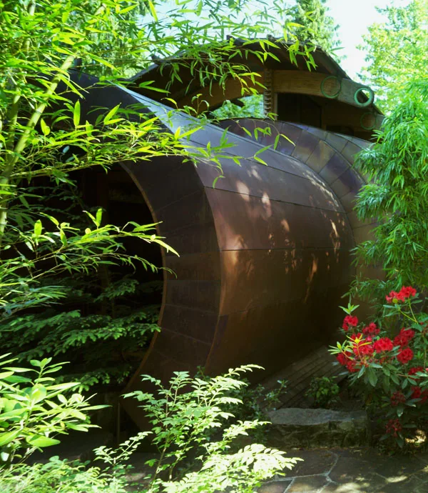 Curved metal roof element integrated in a landscaped garden at the Wilkinson Residence by Robert Harvey Oshatz Architect.