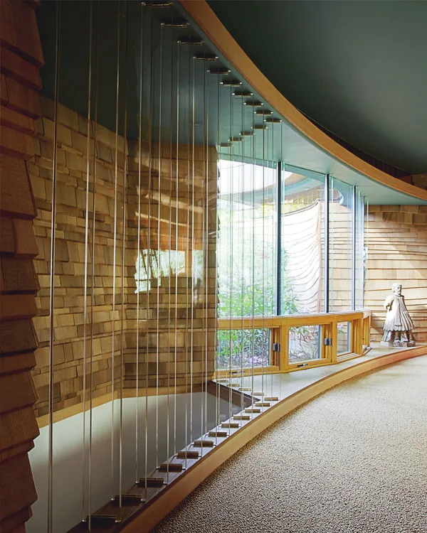 Interior view of Wilkinson Residence showing a curved wall with stone texture and a built-in wooden bench along floor-to-ceiling windows.