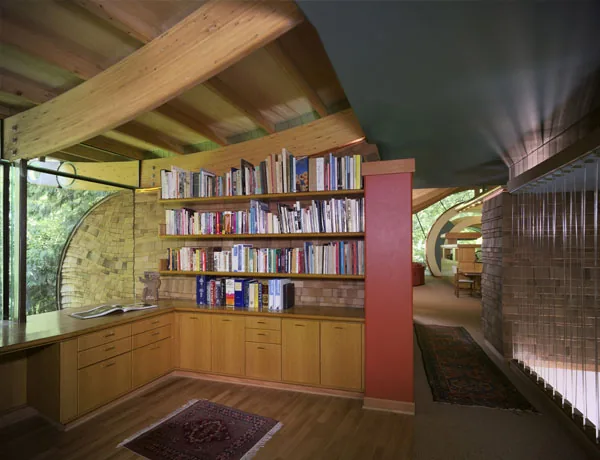 The Wilkinson Residence features a wood-paneled library corner with built-in shelving and large circular windows designed by Robert Harvey Oshatz Architect.