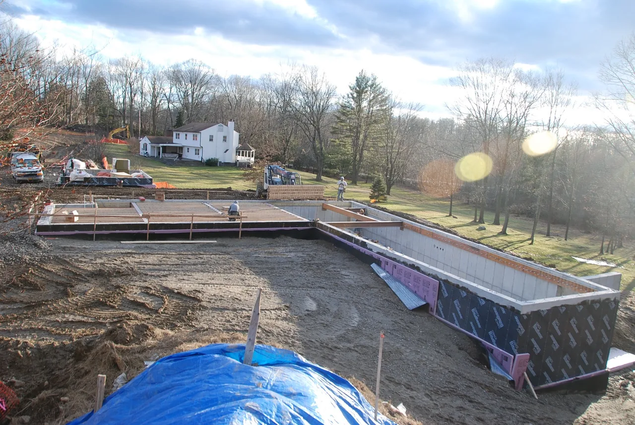 Construction site showing foundation walls, rebar reinforcement, and initial wood framing for House 432 by Robert Siegel Architects.