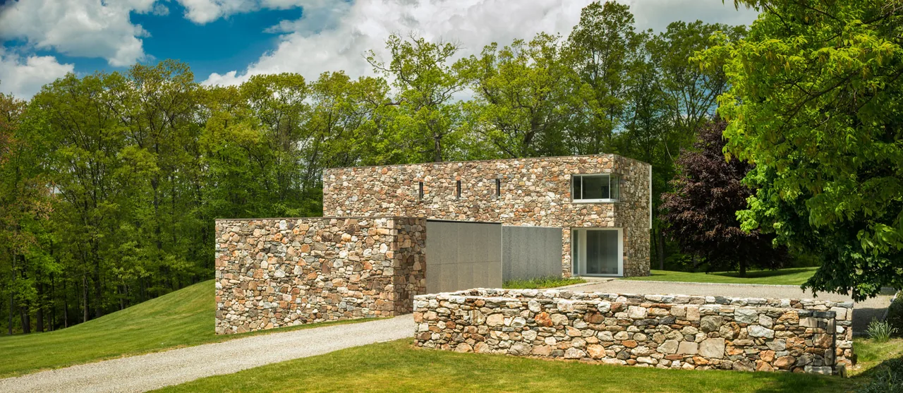 House 432 features a stone exterior with large windows overlooking a lawn and surrounded by mature trees.
