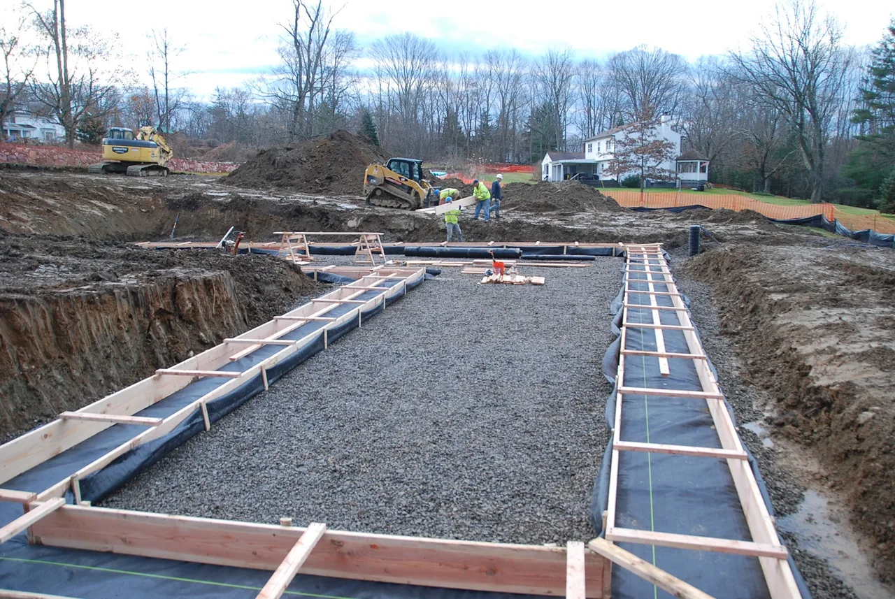 Foundation preparation with wooden formwork and gravel at the House 432 construction site.