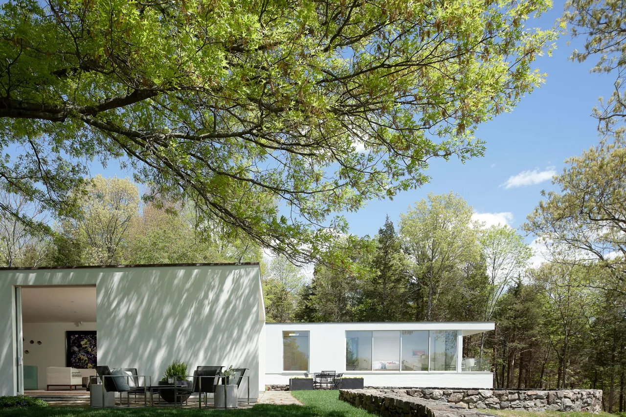 House 125 by Robert Siegel Architects features modern white walls with extensive glazing facing a natural setting.