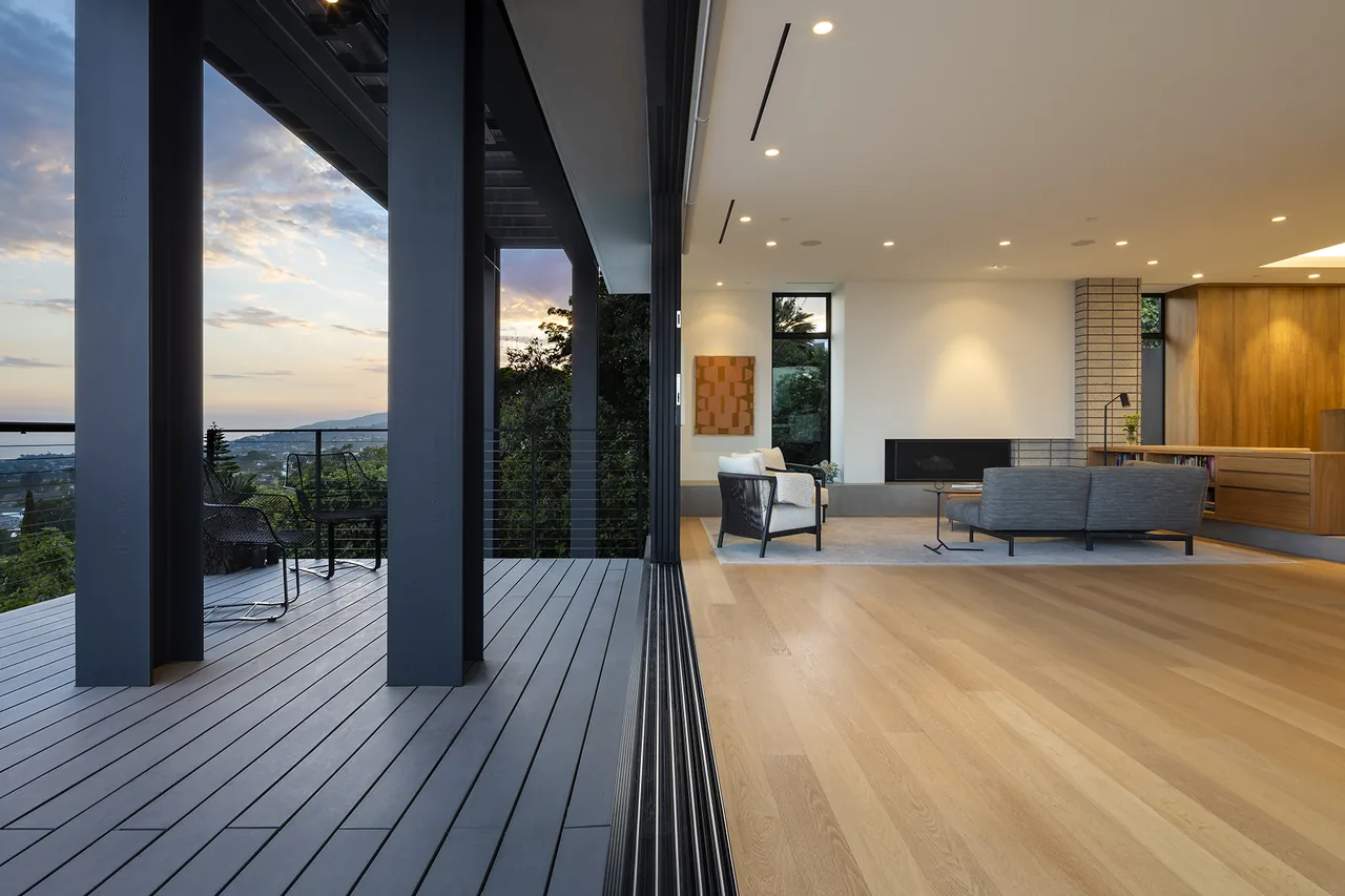 The living room features a large glass sliding door that opens to a spacious covered deck with views of the surrounding landscape.